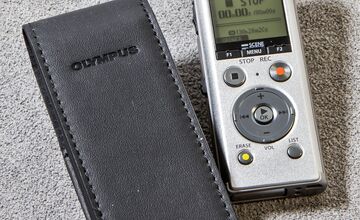 Ansicht auf ein silberfarbenes Gerät mit danebenliegender schwarzer Hülle in Lederoptik.