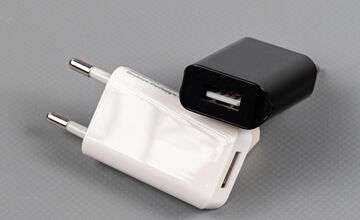 Ansicht auf das weiße Netzteil. Ein Schwarzes liegt schräg dahinter.