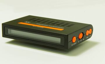 Ansicht auf den Funkreisewecker im schwarzen Gehäuse mit orangenen Tasten.