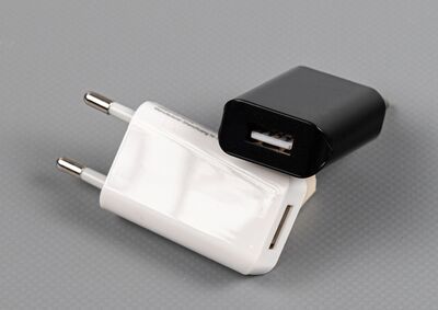 Ansicht auf das weiße Netzteil. Ein Schwarzes liegt schräg dahinter.