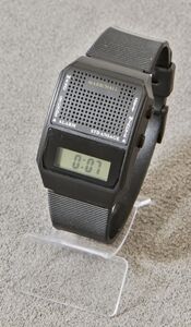 Ansicht auf die schwarze Uhr mit Display in einem transparenten Ständer.