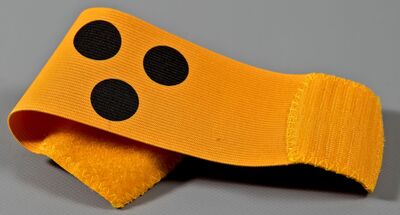 Ansicht auf die fgelbe Armbinde mit drei schwarzen Punkten.